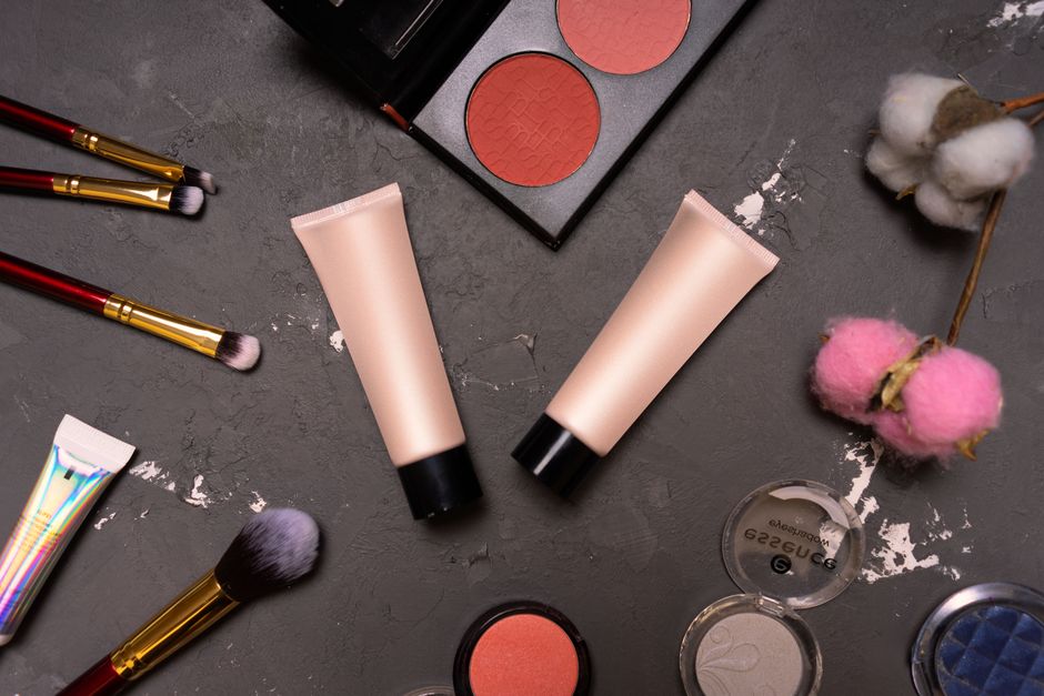 A stylish flat lay showcasing cosmetics including brushes and creams on a dark background.