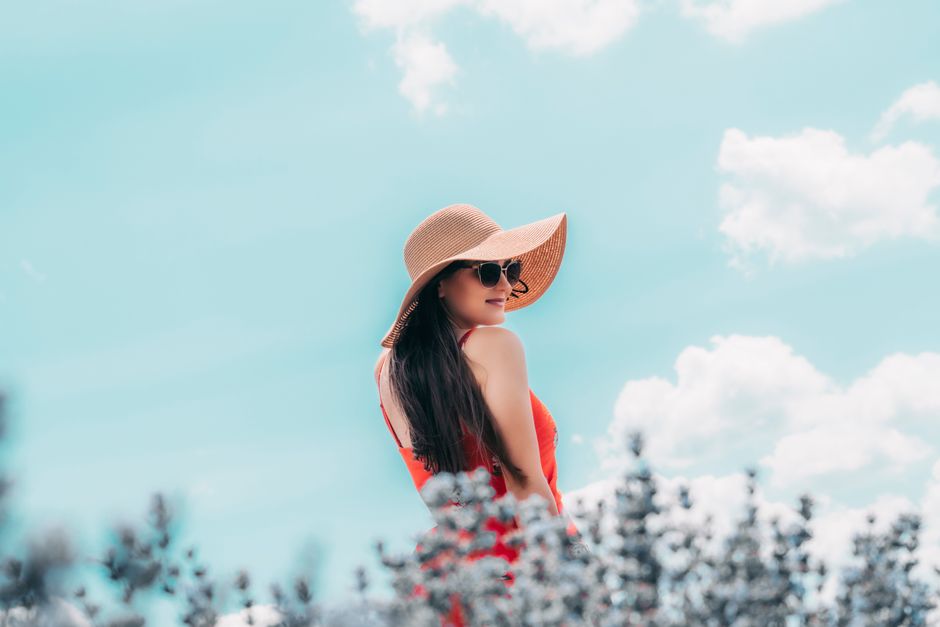 Back view young content brunette wearing trendy hat with wide brims and sunglasses standin