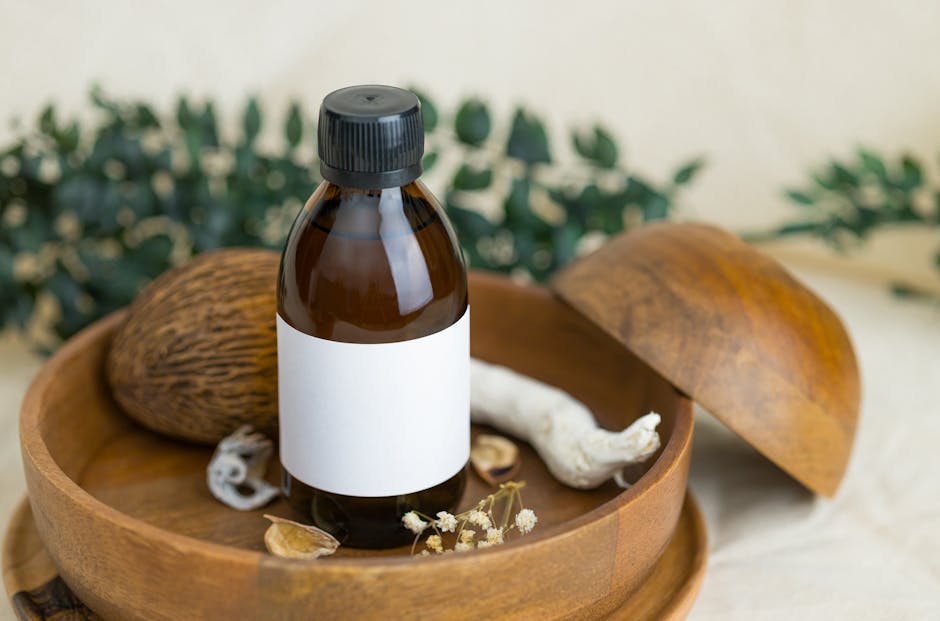 A brown glass bottle with a blank label placed on a wooden plate surrounded by botanical elements, ideal for cosmetic and natural product themes.