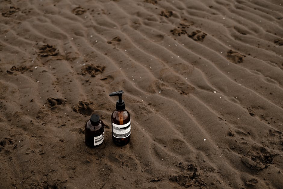Eco-friendly skincare bottles on a natural sandy beach setting, emphasizing sustainability.