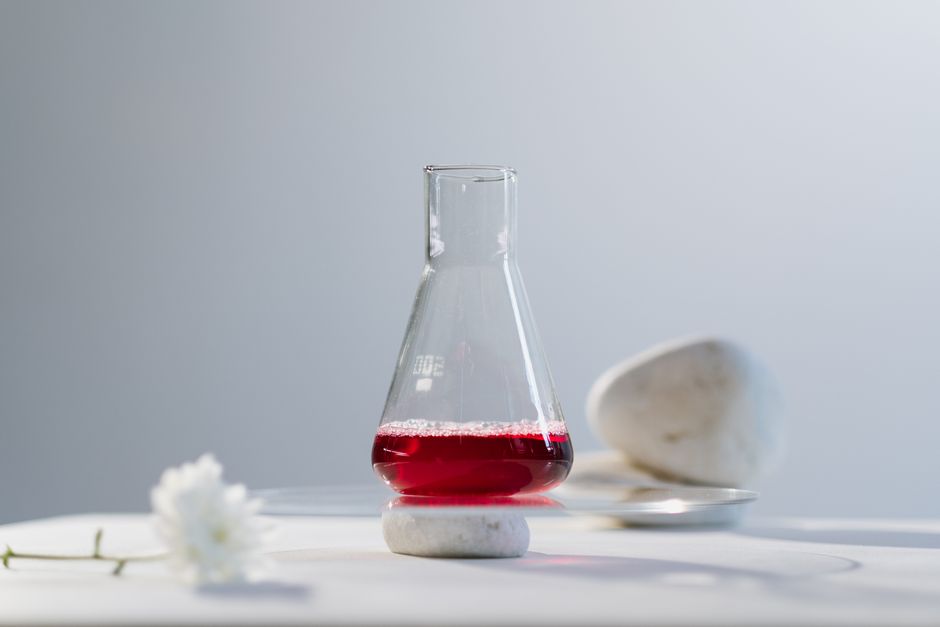 A minimalist setup featuring a flask with red liquid in a science lab setting.