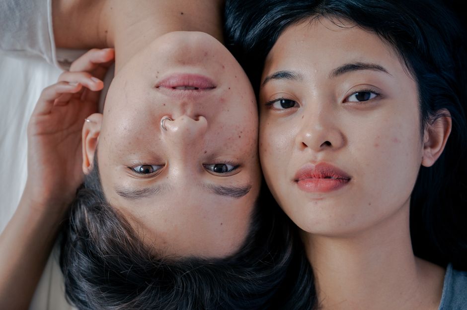 Close-up portrait of two women lying together on a bed, showcasing affection and love.