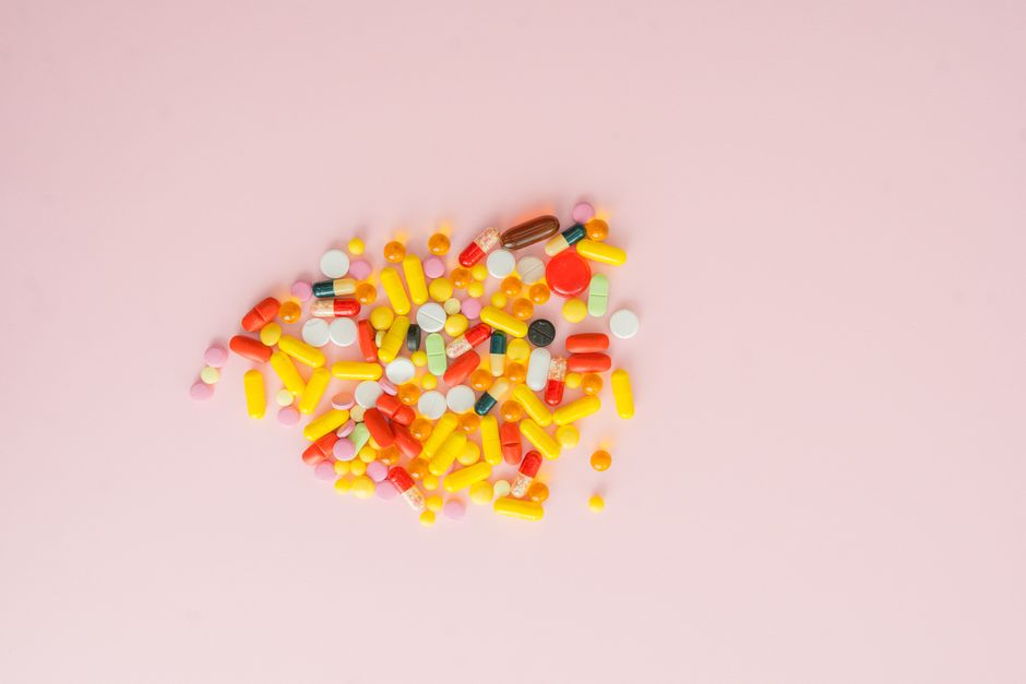 A vibrant collection of various pills and capsules on a soft pink background, emphasizing medication diversity.
