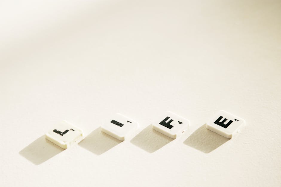 Close-up of Scrabble tiles spelling 'Life' with dramatic shadows on a light background.