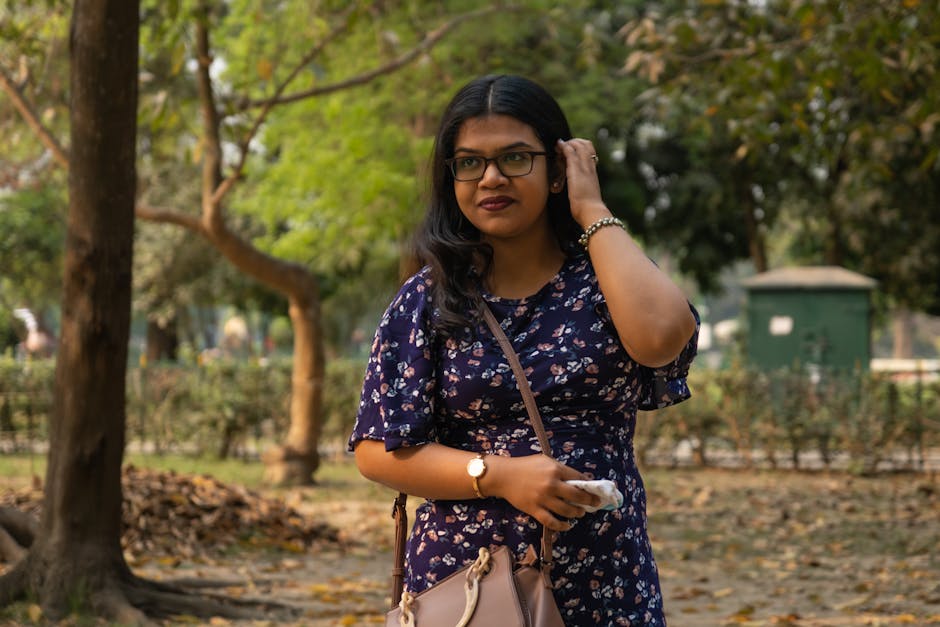 Woman in a floral dress enjoying a walk in a sunny park during early fall.