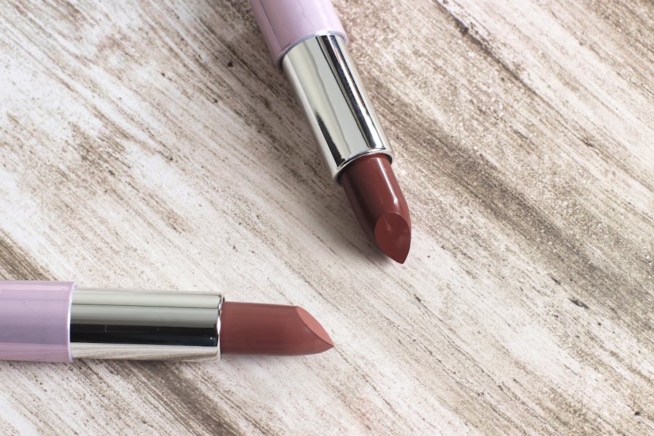 Close-up of two elegant lipsticks on a rustic wooden surface, showcasing beauty and style.