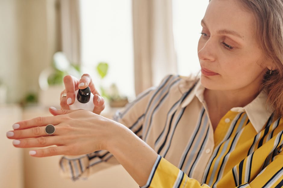 A woman applying hand cream in a bright room, showcasing skincare routine with striped attire.