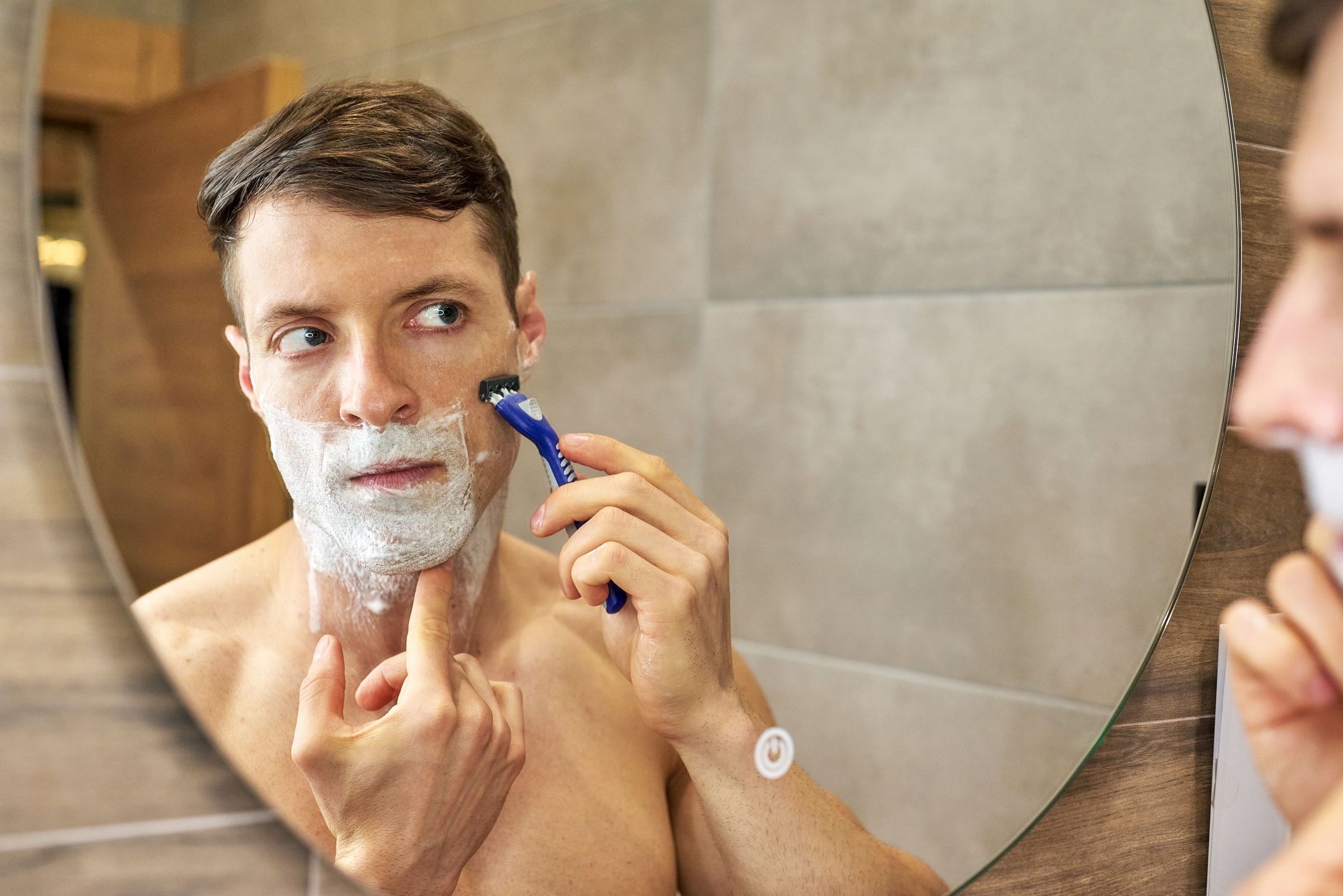 Man shaving in front of a bathroom mirror