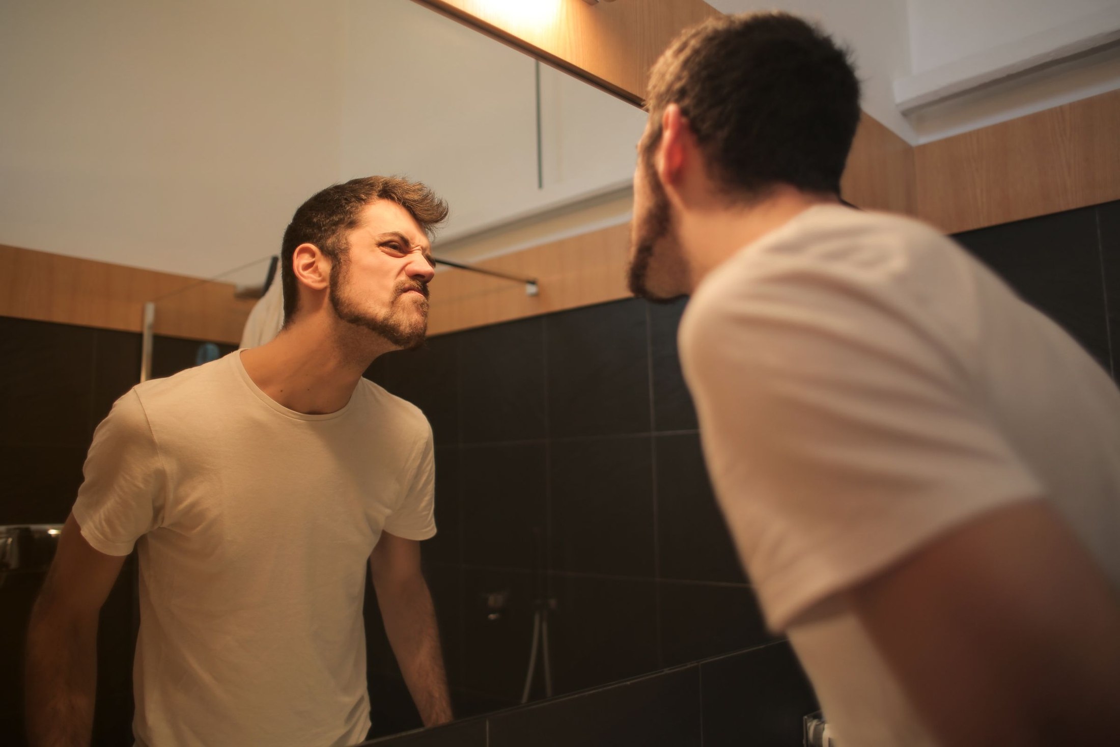 Man checking his face in the bathroom mirror