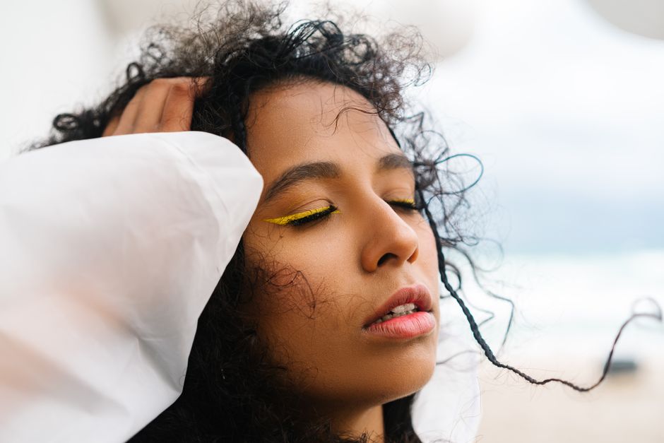 Portrait of a serene woman with curly hair, eyes closed, embracing tranquility.