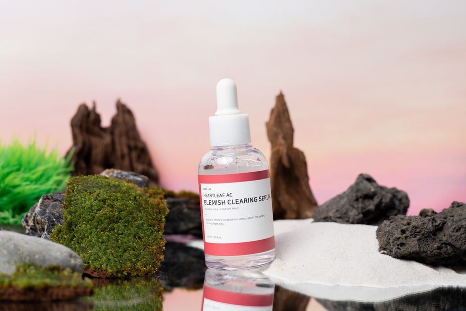 Close-up of Heartleaf AC Blemish Clearing Serum bottle surrounded by natural elements.