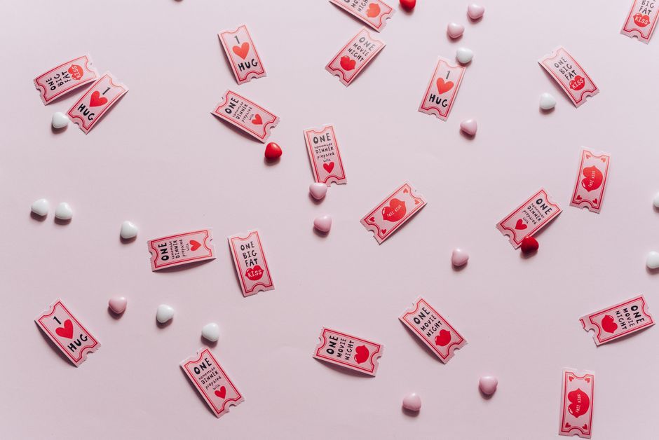 Romantic flat lay of heart candies and love tickets on a soft pink background, perfect for