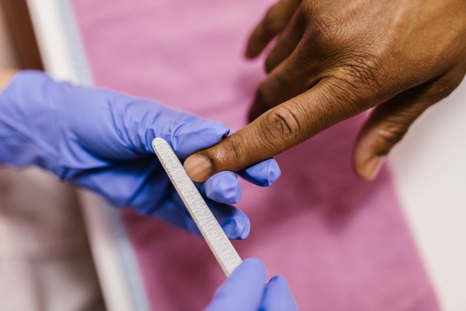 Close-up of a manicure being performed with a nail file on a hand.